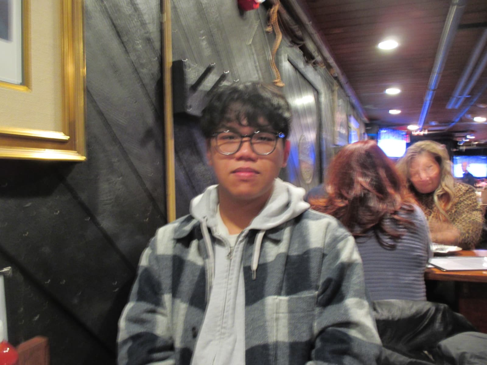 Erik in a plaid flannel jacket at a dimly lit, wood-paneled restaurant.